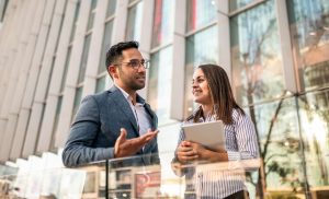 A man and woman speaking to each other outside an office building