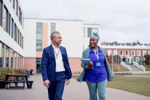 A man and woman speaking to each other outside of a housing complex